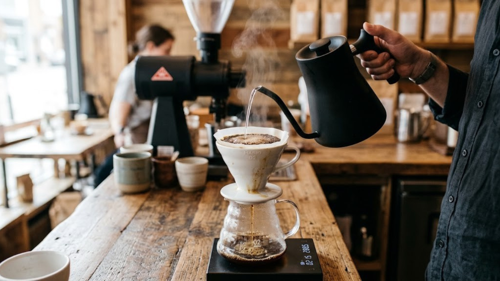Close-up of a gooseneck kettle pouring hot water into a pour-over coffee dripper